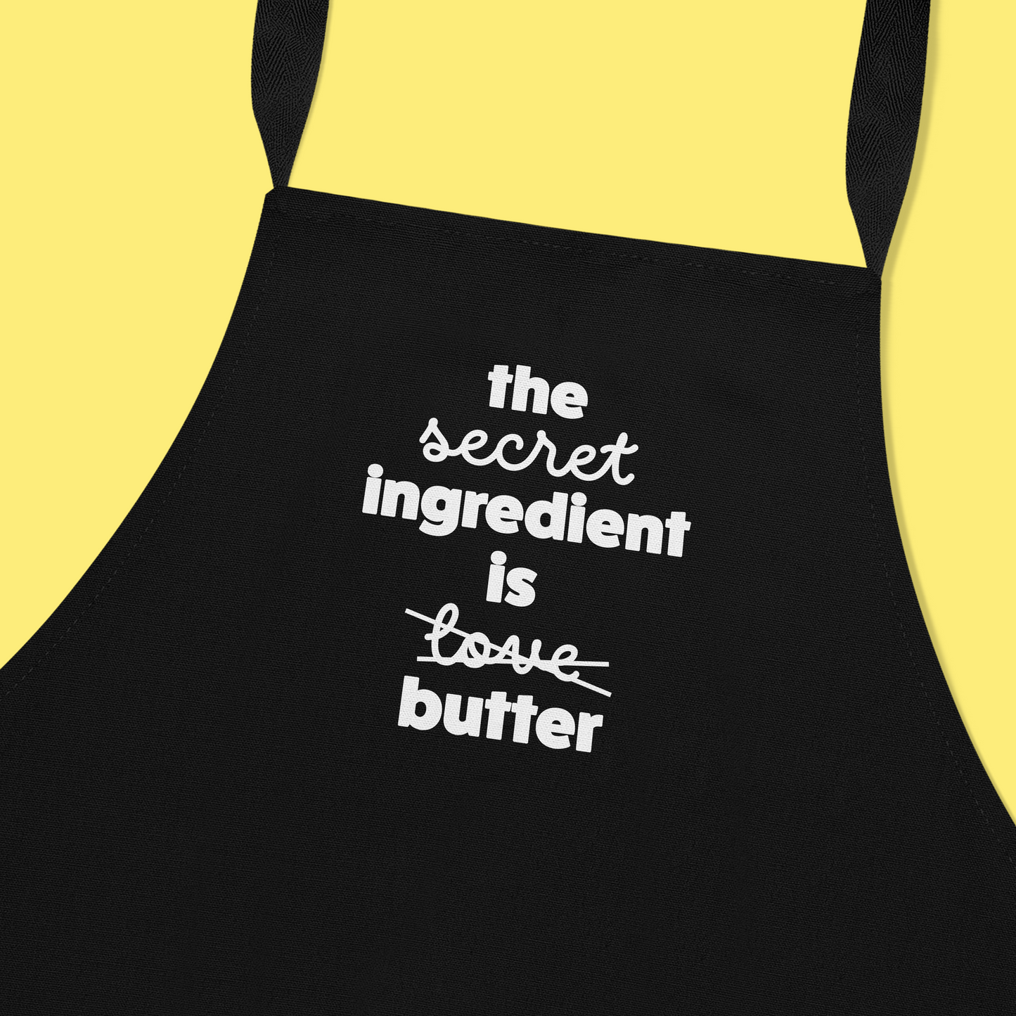 Keukenschort zwart met grappige tekst - The secret ingredient is love/butter