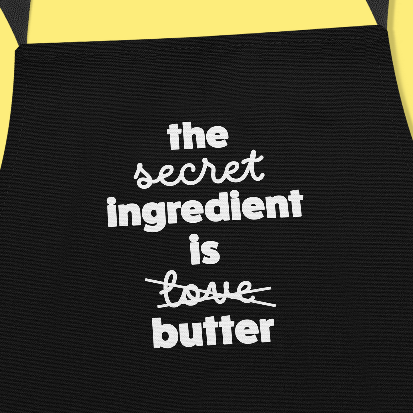 Keukenschort zwart met grappige tekst - The secret ingredient is love/butter